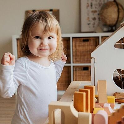 Altdeutsche Mädchennamen Mädchen spielt in einem Kinderzimmer vor einem weißen Puppenhaus