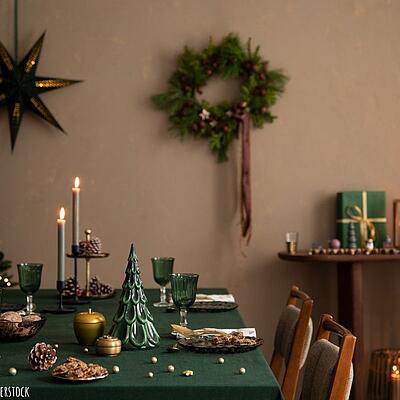 Gedeckter Weihnachtstisch in grünen Farben gehalten und mit verschiedener Dekoration