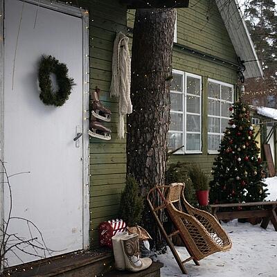 Weihnachtlich geschmückter Hütteneingang mit Schlitten davor