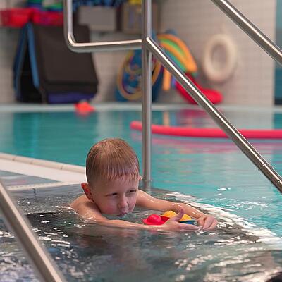 Sicherer Spaß im Wasser Kind schwimmt auf Trainerin zu
