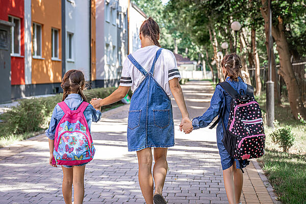 Mutter mit Töchtern auf dem Weg zur Schule